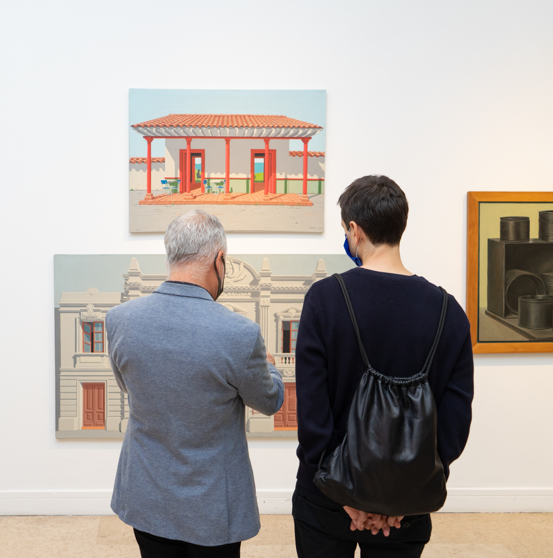 dos hombres de espaldas observando tres pinturas
