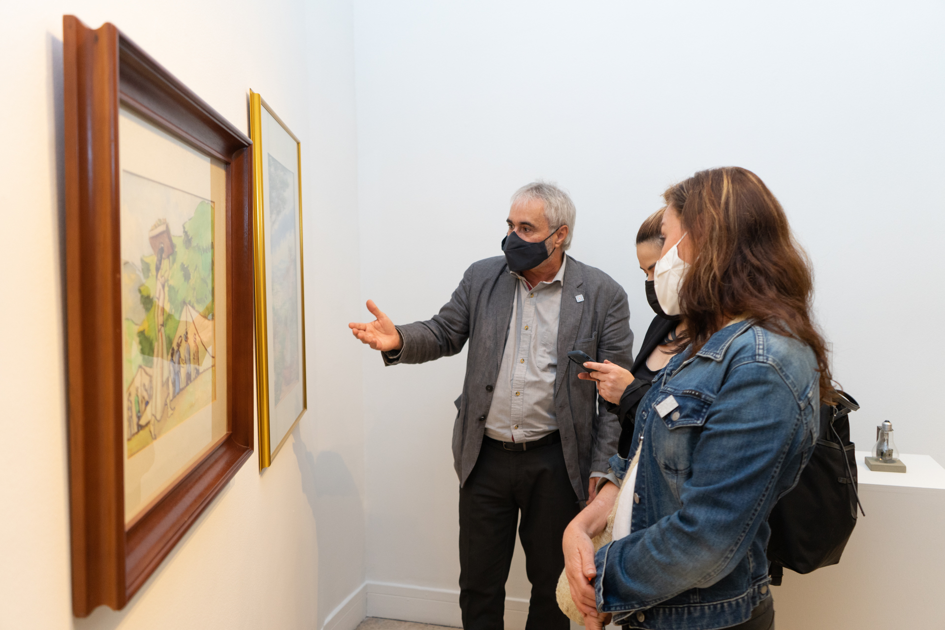 un hombre conversando sobre una pintura con dos mujeres