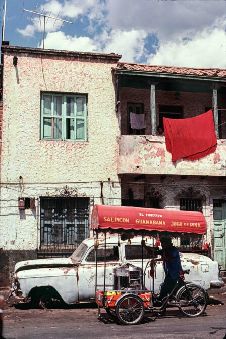 Fachada de una casa con un carrito con ruedas afuera y una persona