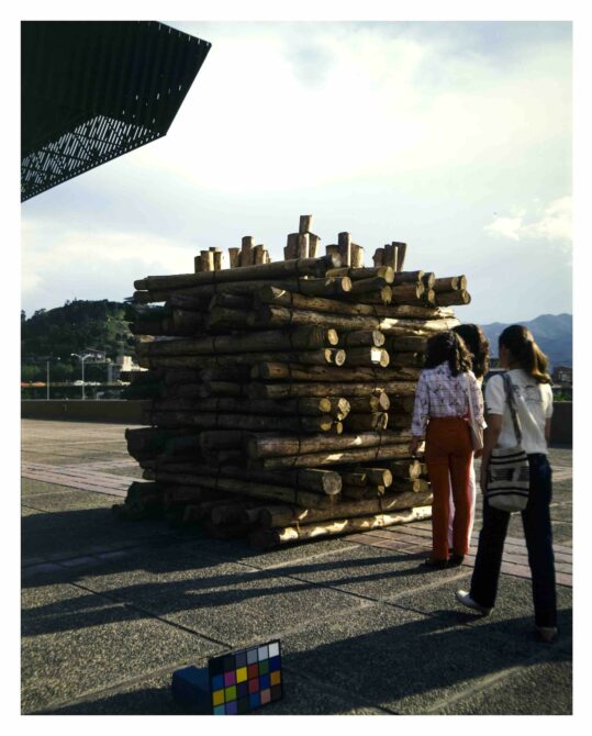 Tres personas mirando una obra construida por leños de madera